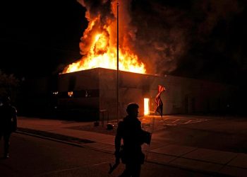 An American flag falls from its pole as police attempt to secure the area after protesters set fire to the department of corrections building, late Monday, Aug. 24, 2020, in Kenosha, Wis. Protests have erupted following the police shooting of Jacob Blake a day earlier. (AP Photo/David Goldman)