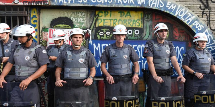 Police officers stand at attention as students protest against the country's latest round of transport fare hikes, in Sao Paulo, Brazil, on January 16, 2015. Amid a marked economic downturn and high inflation, bus fares went up in Sao Paulo, Brazil's largest city, from 3 to 3.50 reais, and in Rio, the former capital, from 3.0 to 3.40 reais. Rio's 13 percent hike is almost exactly double the current rate of inflation.  AFP PHOTO / NELSON ALMEIDA / AFP PHOTO / NELSON ALMEIDA